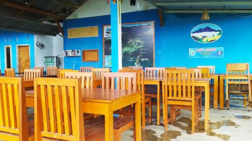 uma sala de jantar com mesas e cadeiras de madeira em Embun Rinjani Homestay em Senaru