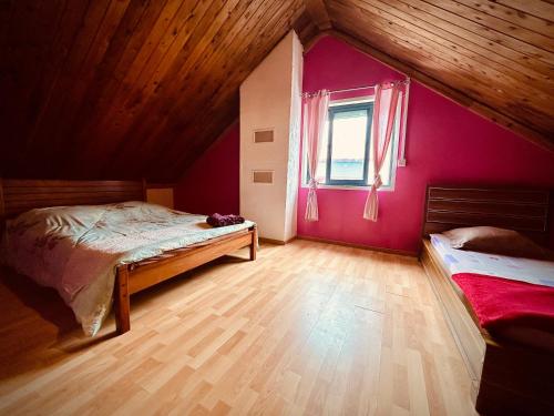 1 dormitorio con paredes rosas y suelo de madera en La Kaz du Volcan-Capacité maximum 10 personnes en La Plaine des Cafres