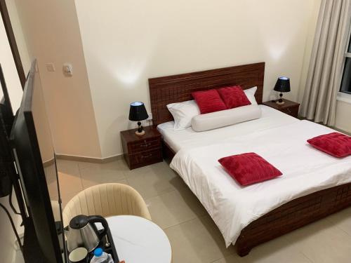 Un dormitorio con una cama con almohadas rojas. en Family rooms with beach view يستضيف مكان الإقامة هذا العائلات فقط, en Ajman
