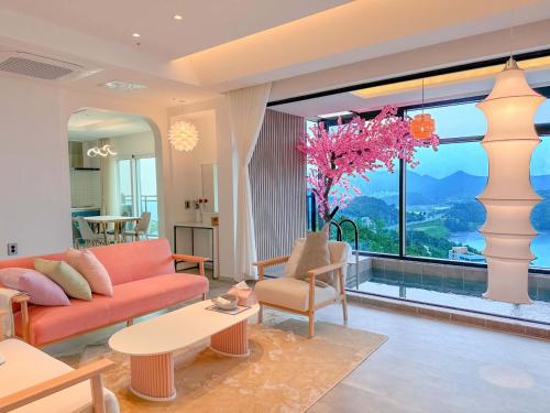 a living room with a red couch and a large window at Simer Resort & Pool Villa in Yeosu