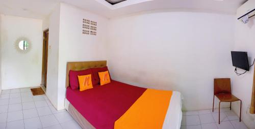 a bedroom with a bed with colorful blankets and pillows at Angel Home Stay by Nusalink in Warungsergon
