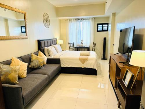 a living room with a couch and a bed at PREMIUM CONDO AT BRENTHILL BAGUIO in Baguio