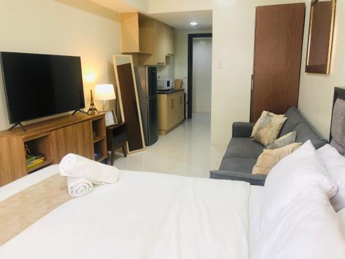 a hotel room with a bed and a tv and a couch at Brenthill Premium Condo Baguio City with Generator in Baguio