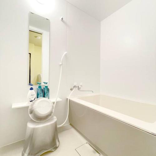 a white bathroom with a toilet sitting next to a bath tub at InatoRelux in Inatori