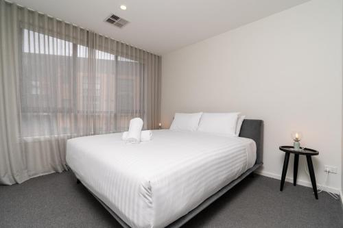 a white bed in a room with a large window at Contemporary Tri-Level APT in a Prime Central Spot in Canberra