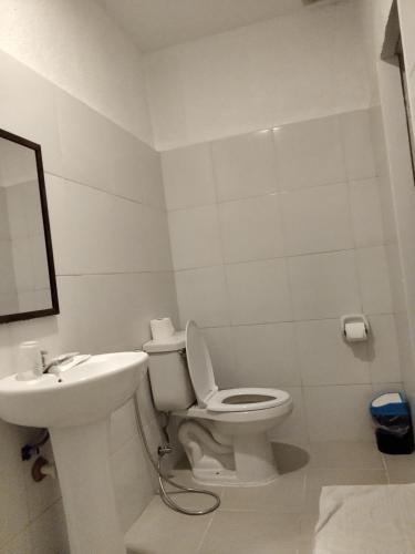 a white bathroom with a toilet and a sink at Moalboal Beach Front Hotel in Moalboal