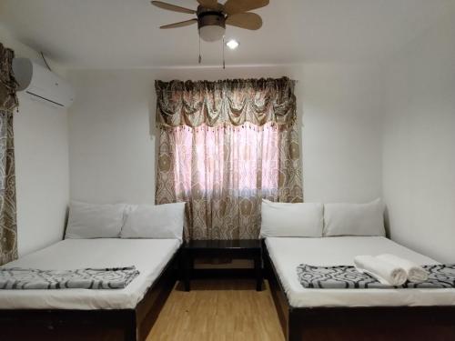 two beds in a room with a window at Moalboal Beach Front Hotel in Moalboal