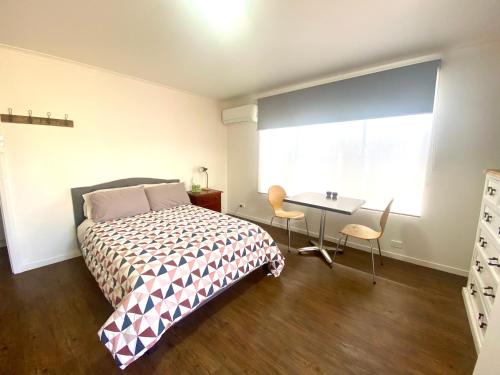 1 dormitorio con cama, escritorio y ventana en Strahan Accomodation Units, en Strahan