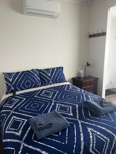 ein Bett mit einer blauen und weißen Decke und einem Nachttisch in der Unterkunft Strahan Accomodation Units in Strahan