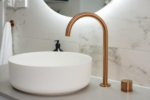 a white sink with a gold faucet in a bathroom at Historic Beauty in the CBD with Parking & WiFi in Launceston