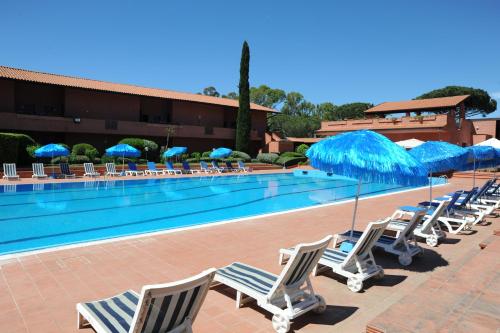 a pool with lounge chairs and blue umbrellas at Hotel Residence Villa San Giovanni in Portoferraio