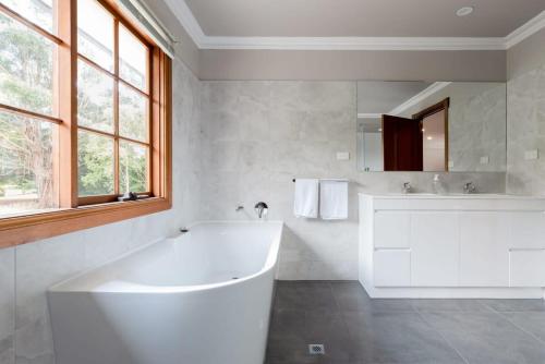 Baño blanco con bañera y lavamanos en Gracelands Swiss Inspired Home with Gorgeous Grounds, en Hadspen