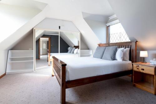 1 dormitorio con 1 cama grande y espejo en Gracelands Swiss Inspired Home with Gorgeous Grounds, en Hadspen