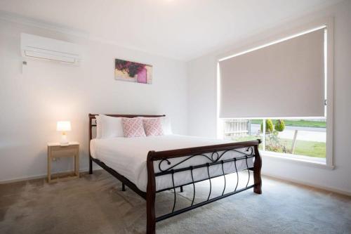 1 dormitorio con cama y ventana grande en Homely Suburban Delight With Parking & Wi-fi, en Kings Meadows