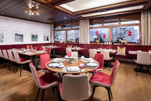 ein Restaurant mit Holztischen und roten Stühlen in der Unterkunft ALPIN- Das Sporthotel - SKI IN SKI OUT cityXpress, SUMMERCARD INCLUDED in Zell am See