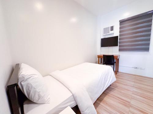 a bedroom with a white bed and a table at SANTOS Pension House in Manila