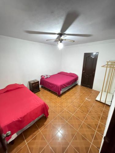 Cette chambre comprend deux lits et un ventilateur de plafond. dans l'établissement Casa genesis, à Panajachel
