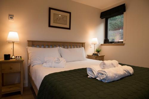 een slaapkamer met een bed met handdoeken erop bij Forest Corner Luxury Home with Hot Tub in North Ballachulish