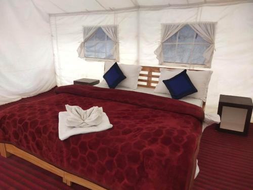 - une chambre avec un grand lit rouge dans une tente dans l'établissement Northern Valley Camp - Nubra, à Hundar