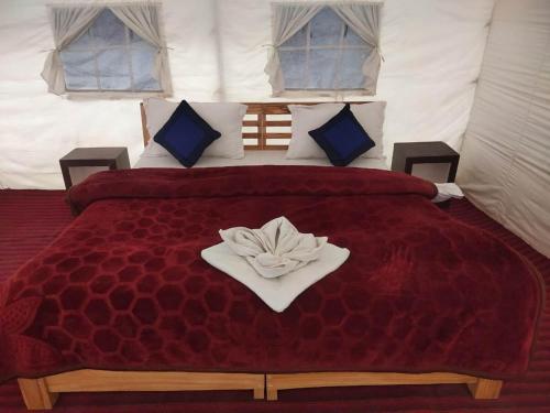- un grand lit rouge avec une serviette dans l'établissement Northern Valley Camp - Nubra, à Hundar