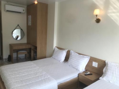 a bedroom with two white beds and a mirror at Sea Balcony Hotel in Cat Ba