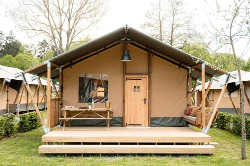 a tent with a wooden porch in a yard at De Limes Hoeve Safaritent A1 in Ingen