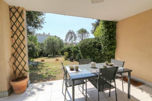 - une table et des chaises sur une terrasse avec vue sur la cour dans l'établissement Charming & bright flat with AC Garden 300m and Closed Garage - BENAKEY, à Cannes