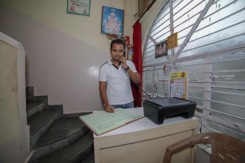 Un uomo che parla al cellulare alla scrivania di SPOT ON Shraddha Hotel a Nagpur