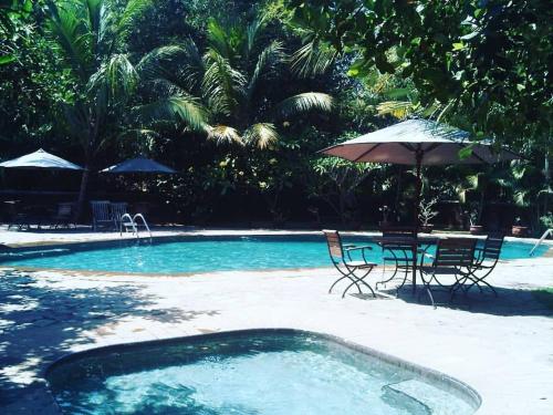 - une piscine avec une table, des chaises et un parasol dans l'établissement Hills Joglo Villa, à Ungaran