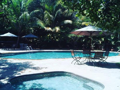 a pool with a table and chairs and an umbrella at Hills Joglo Villa in Ungaran