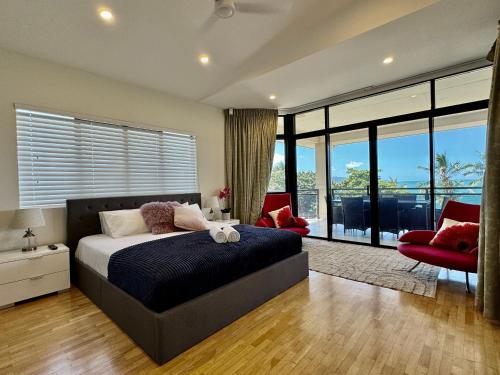 a bedroom with a large bed and a red chair at Lighthouse Apartments on The Strand - Penthouse in Townsville