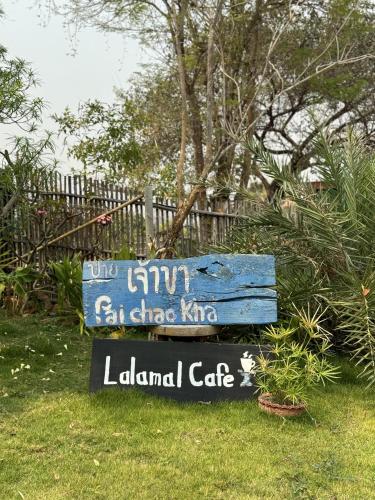 a blue sign in the grass next to a fence at Pai Chao Kha in Pai