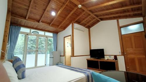 a bedroom with a bed and a tv and a window at Xitou Tianpin Homestay in Lugu