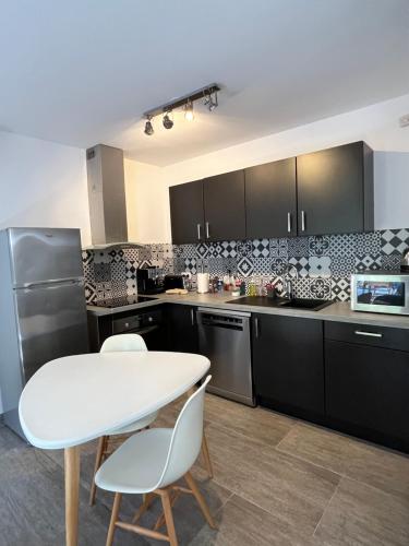 une cuisine avec des armoires noires et une table et des chaises blanches dans l'établissement Magnifique Bergerie en Pierre, à Brando