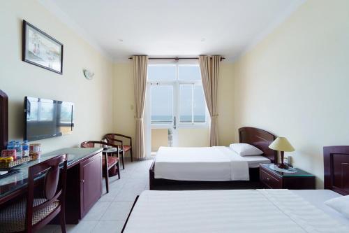 Una habitación de hotel con dos camas y un televisor. en Victory Hotel Old Wing, en Vung Tau