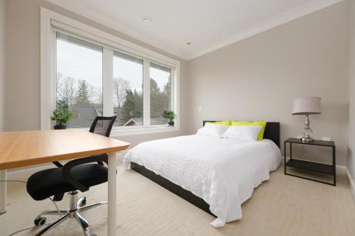 a white bedroom with a bed and a desk and window at Dunbar Luxury Homestay in Vancouver