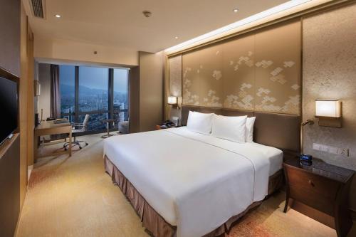 a large white bed in a room with a window at Hilton Yantai in Yantai