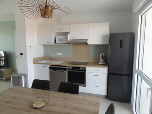 Il comprend une cuisine équipée d'une table et d'un réfrigérateur noir. dans l'établissement Voiles Blanches grand T3, à Leucate