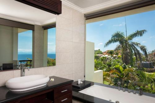 Blue Point Resort and Spa في أُلُواتو: حمام مع نافذة كبيرة مطلة على المحيط
