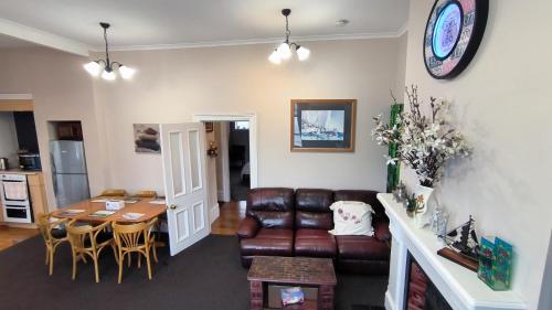 a living room with a leather couch and a table at City Centre Superior Villa 3 large Double bedrooms in Christchurch