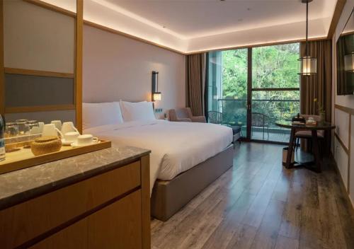 安吉県にあるHentique Resort Anjiのベッドと大きな窓が備わるホテルルームです。