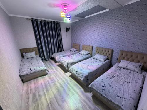 three beds in a room with purple walls at “DACHA” Hi-Tech by Dubai in Aranchi