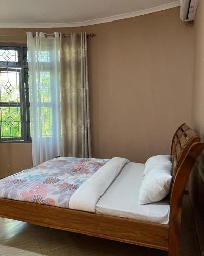 1 cama en un dormitorio con ventana en KARUSIRO FARM AND COUNTRY PARK, en Kibaha