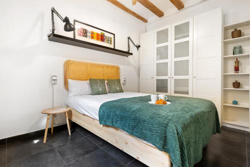 a bedroom with a bed with a green blanket at Lodging Apartments Almirall Beach 22 in Barcelona