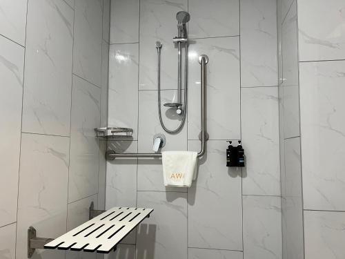 uma casa de banho com um chuveiro com um banco em AWA Hotel em Rotorua