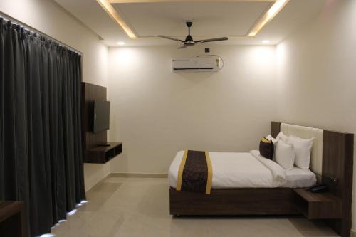 a bedroom with a bed and a ceiling fan at Hotel Grand Nitara in Kotdwāra