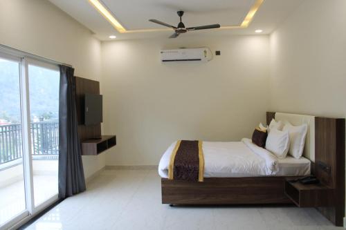 a bedroom with a bed with a ceiling fan at Hotel Grand Nitara in Kotdwāra