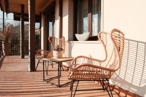 three wicker chairs and a table on a porch at WELCOME TRAVELLER FRIDA'S ROOMs in Caprino Veronese
