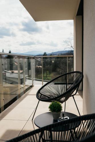 a chair and a table on a balcony with a view at Apartament ACTIV jezioro góry in Żywiec