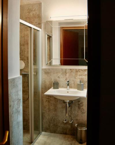 a bathroom with a sink and a shower with a mirror at WELCOME TRAVELLER FRIDA'S ROOMs in Caprino Veronese